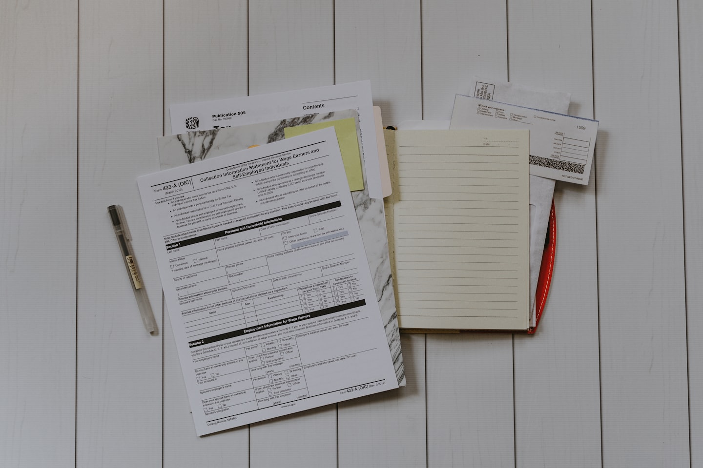 Tax forms and notebook on a wooden desk.